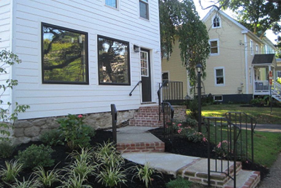 A white house with a brick walkway leading to the front door.