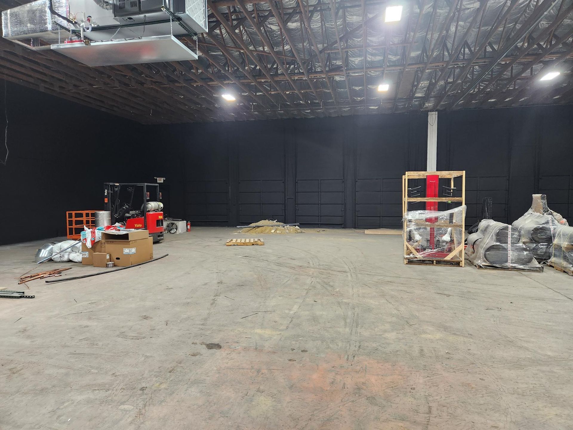 A large empty warehouse with a forklift in the middle of it.