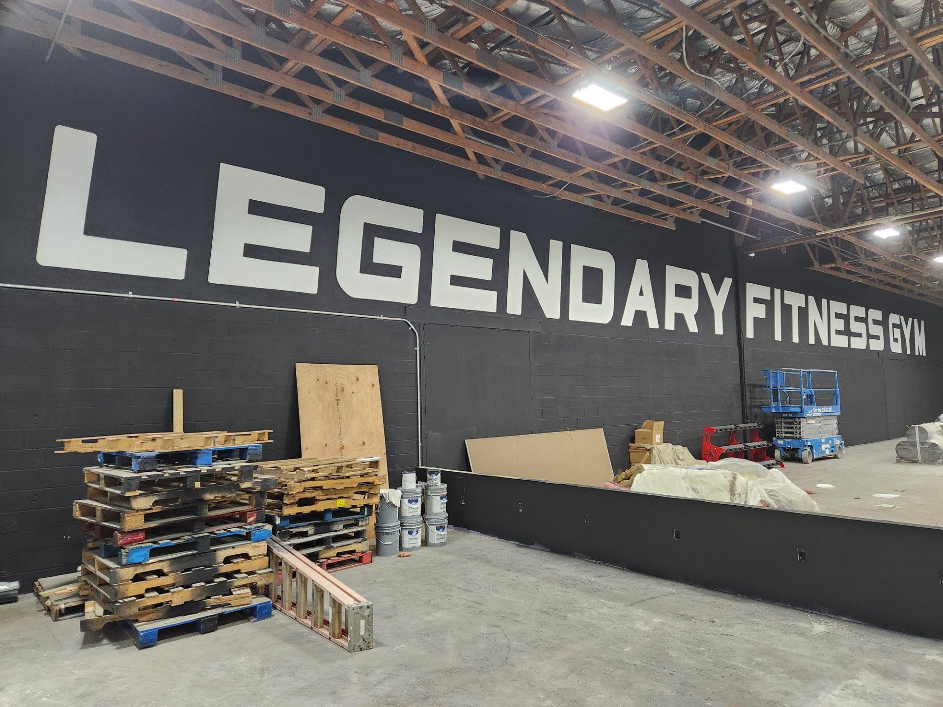 A large black wall with the words legendary fitness gym painted on it