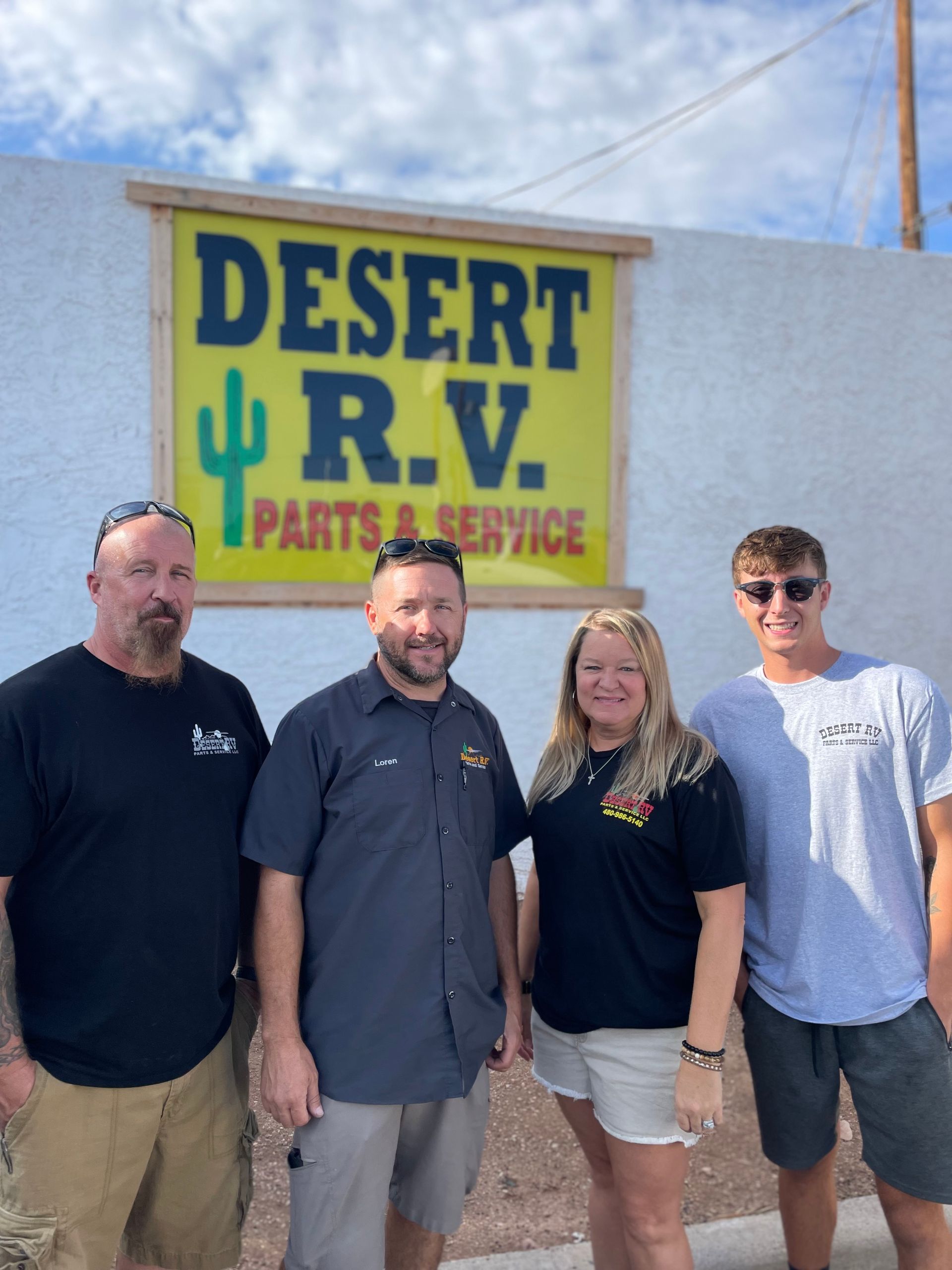 Four people stand in front of a sign that reads 