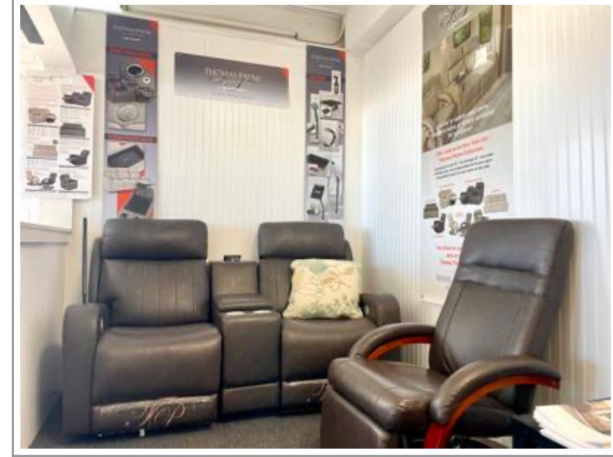 Brown leather reclining furniture in a small room with advertising banners.