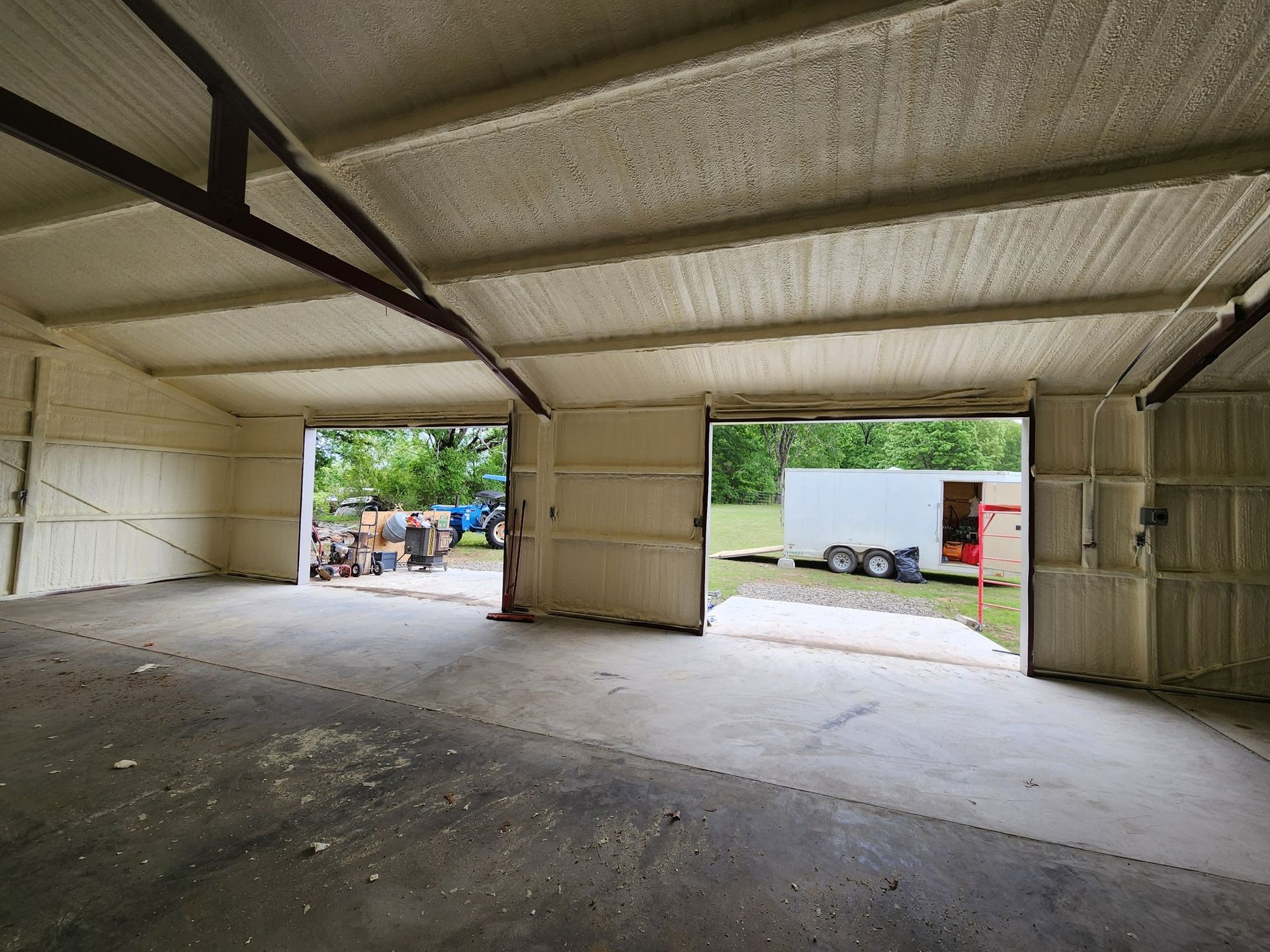 Empty industrial garage with concrete floor and open doorways to the outside
