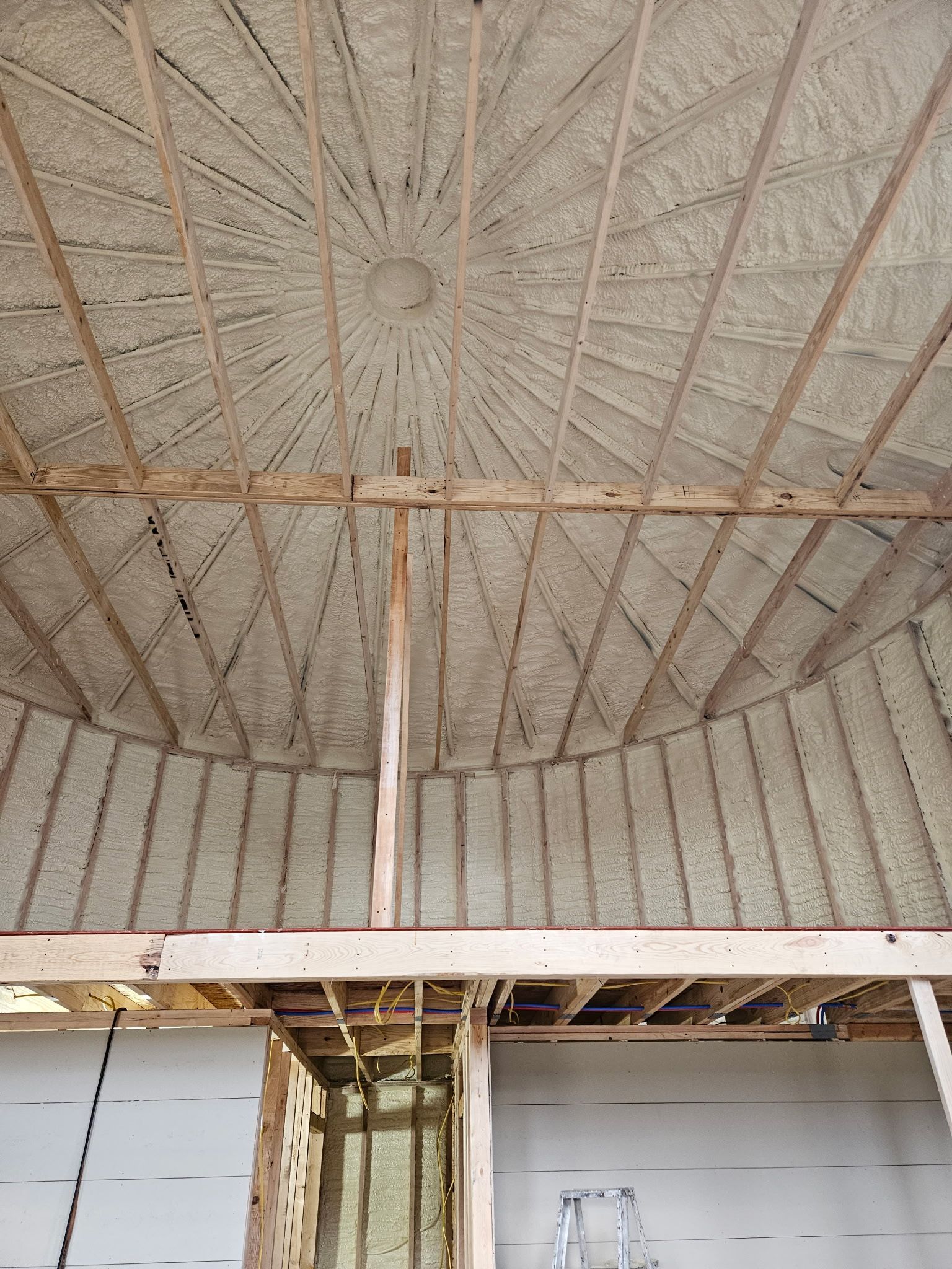 Interior view of a weathered wooden roof with a central support beam and peeling paint below