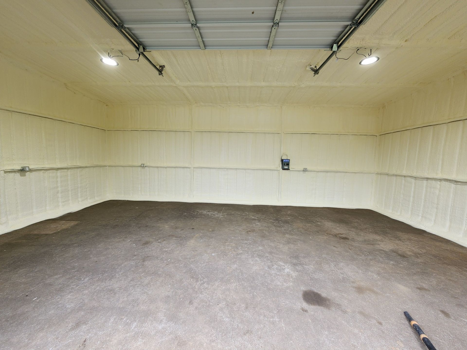 Empty beige garage or storage room with concrete floor and a closed overhead door