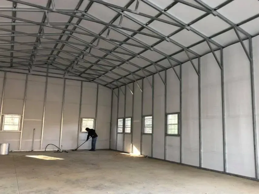 Empty metal-framed warehouse interior with a person working near the back wall