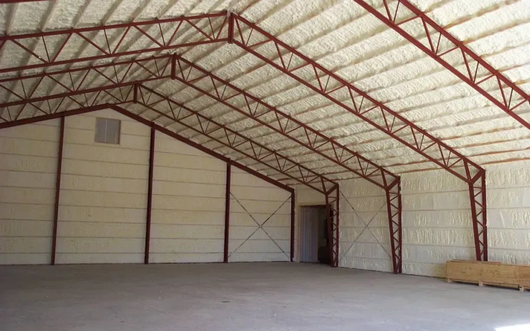 Empty warehouse interior with metal roof trusses, white walls, and concrete floor
