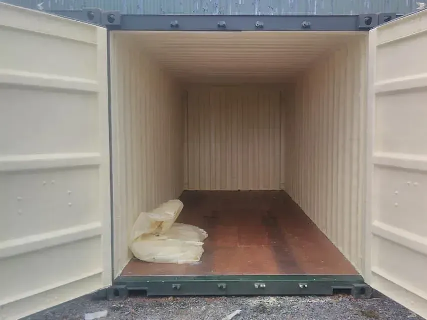Empty shipping container interior with a few white sacks on the floor near the entrance