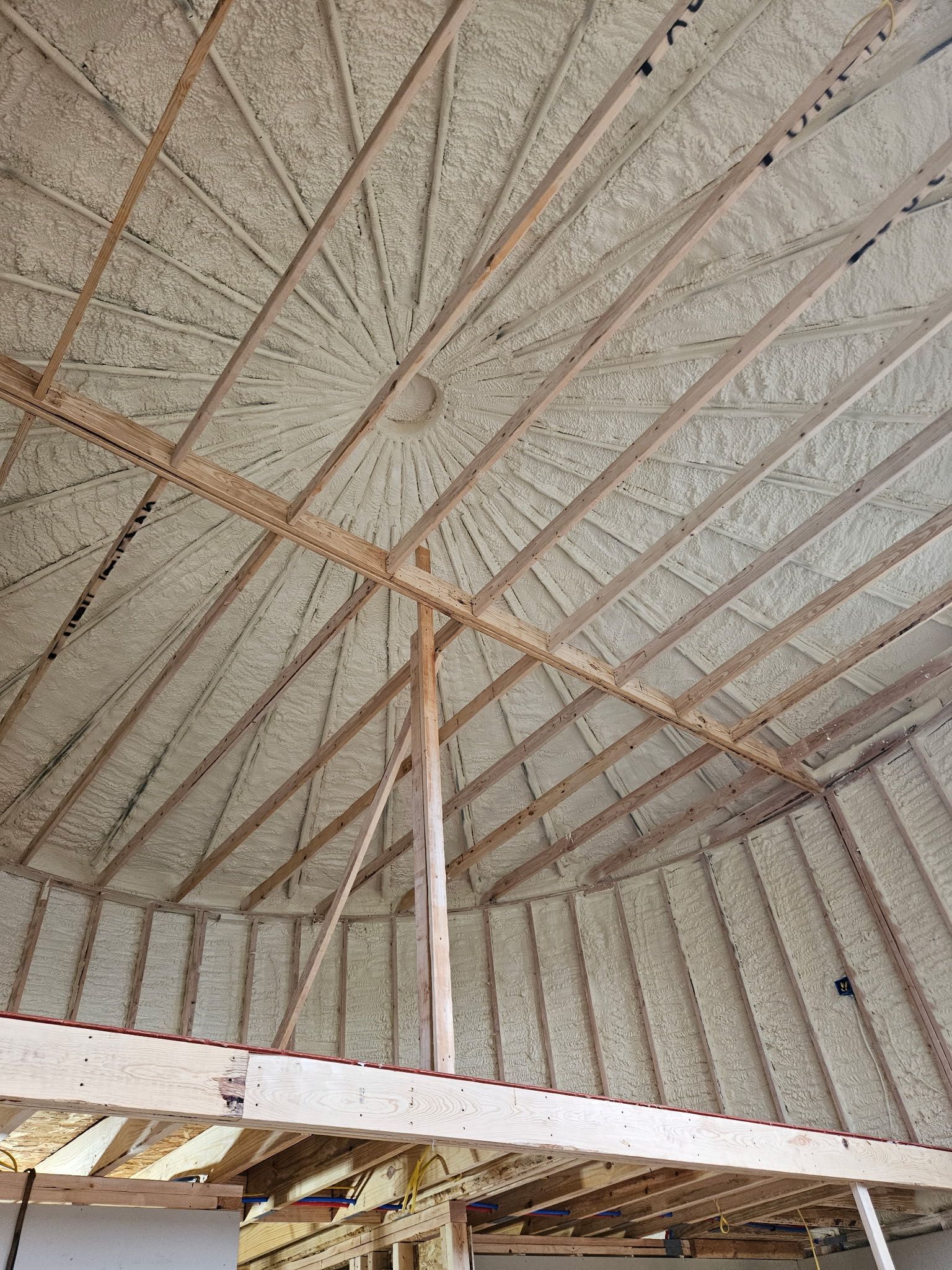 Underside of a corrugated metal roof with wooden rafters and a central support post