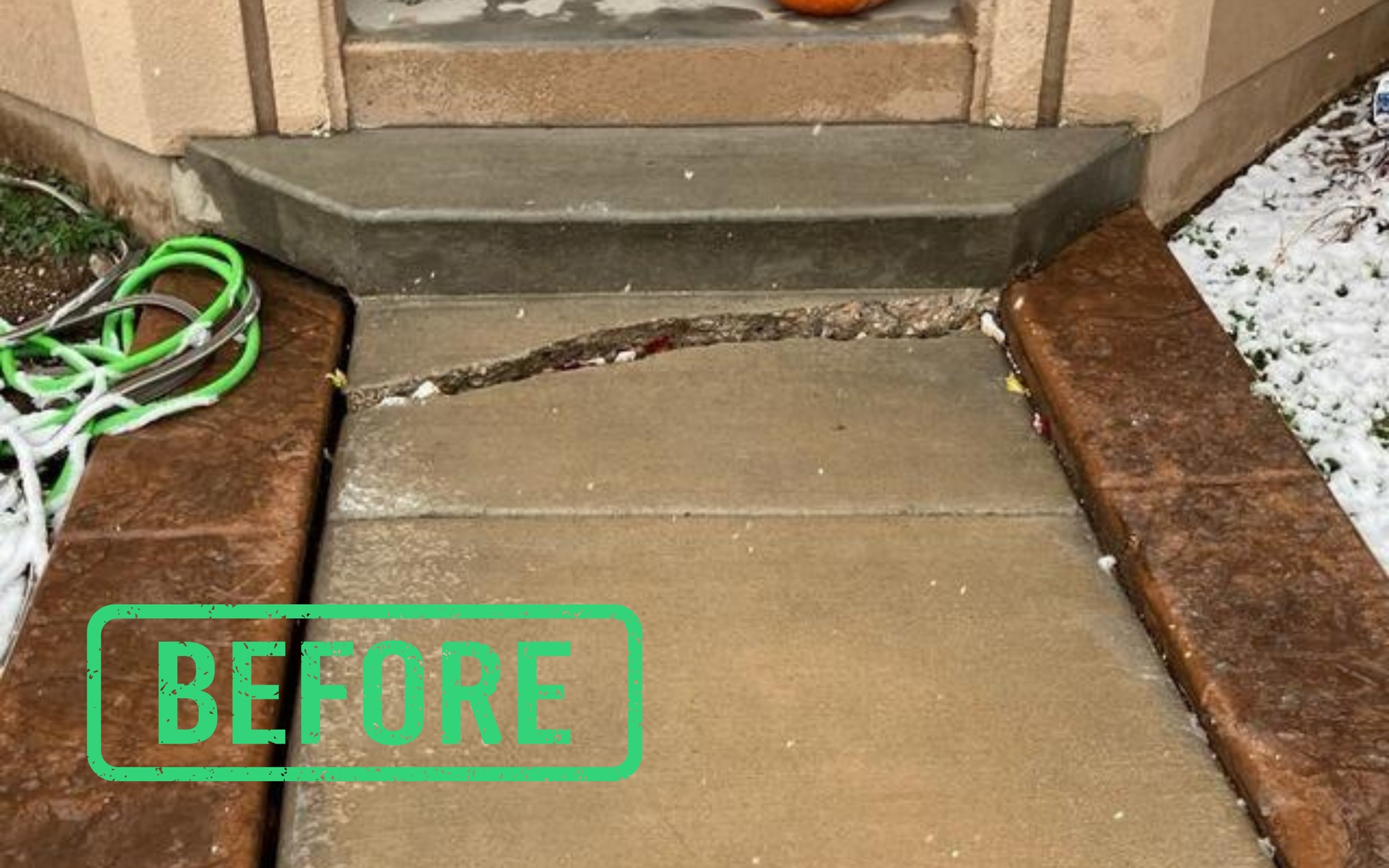Concrete walkway and front steps beside brick walls, with a green hose 