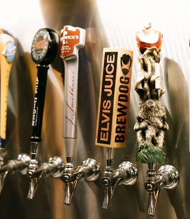 Beer taps with various decorative handles in a bar.