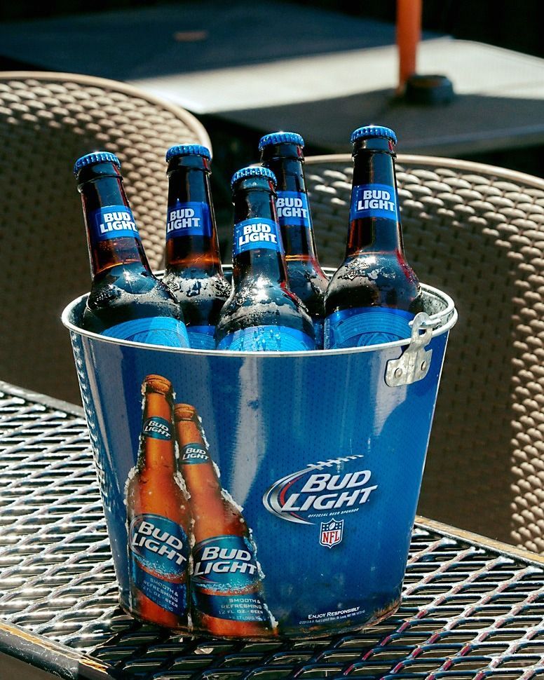 Bucket of blue Bud Light bottles on a sunny patio.