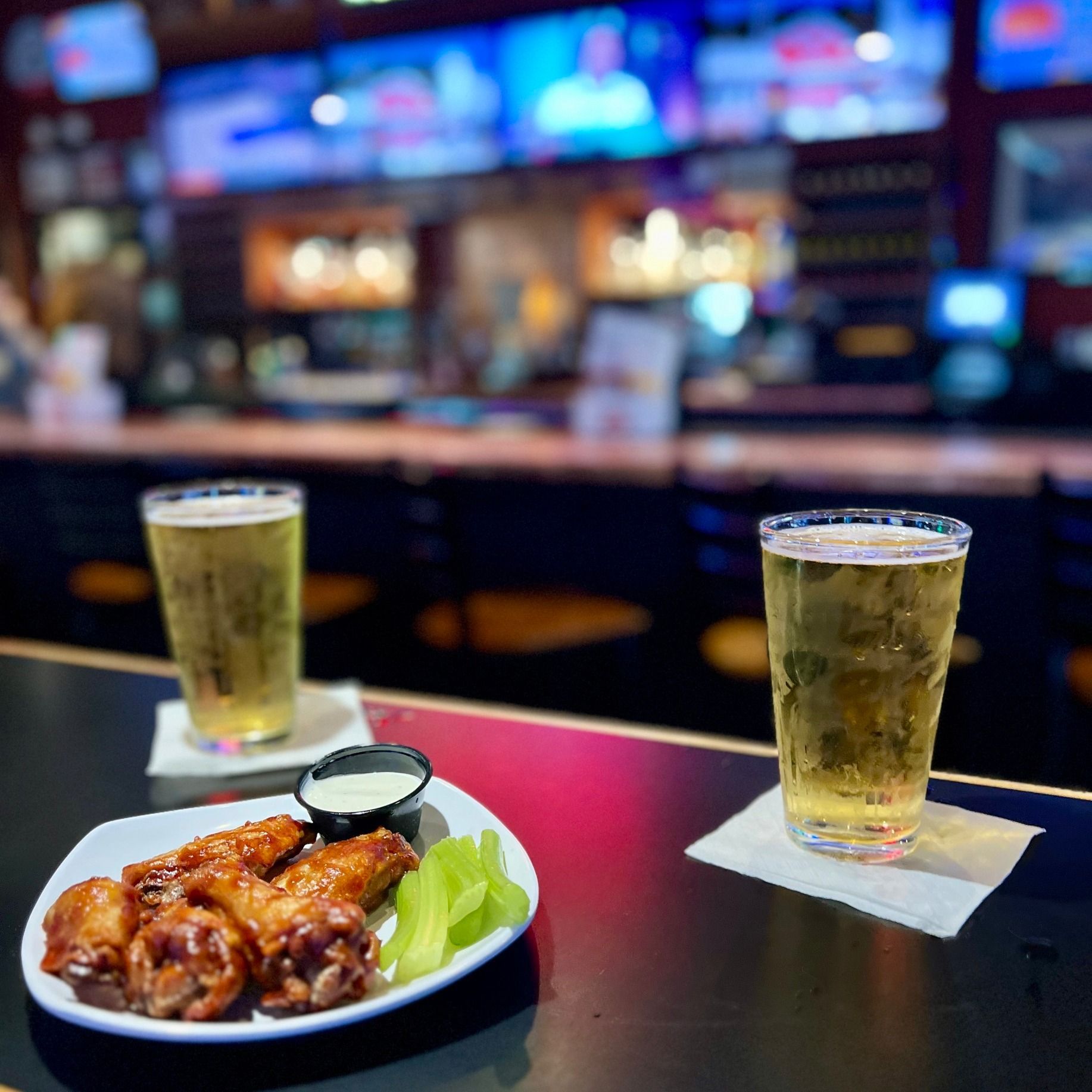 Chicken wings with beer on a bar, inside a bar setting.