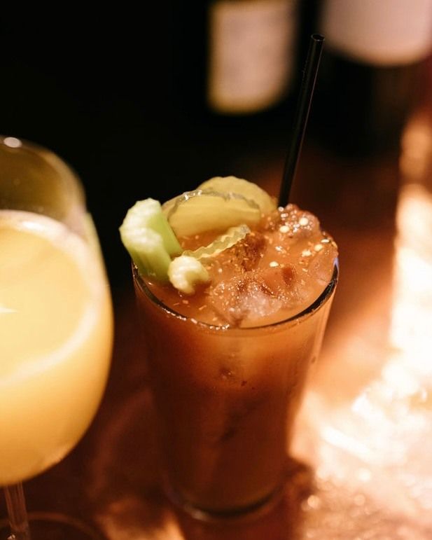 Bloody Mary cocktail garnished with cucumber and pickles, on a bar.