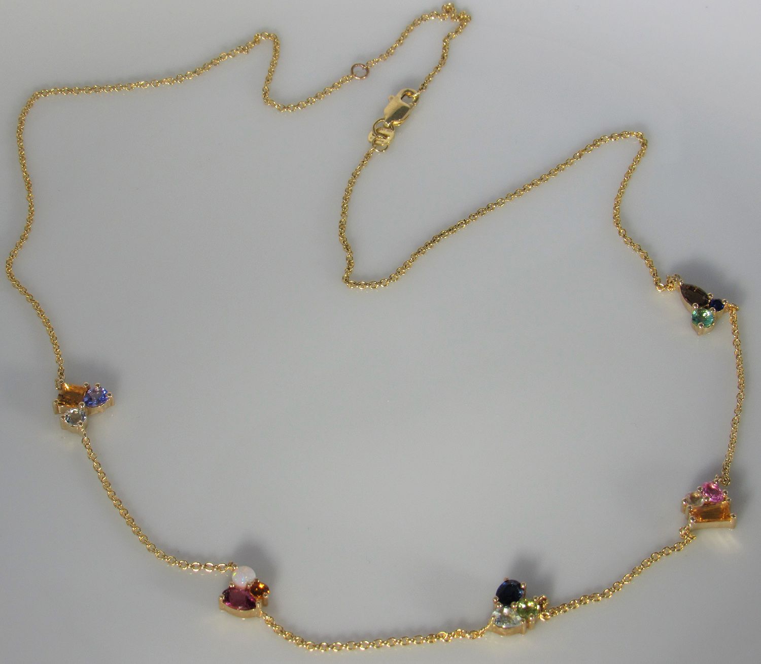 A gold necklace with various colored stones on it
