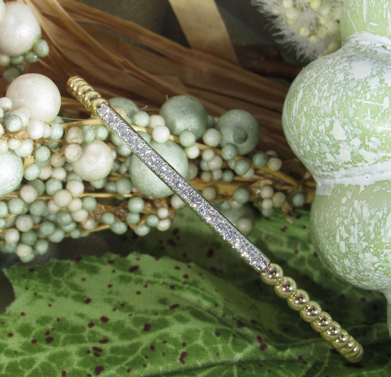 A close up of a bracelet on a green leaf