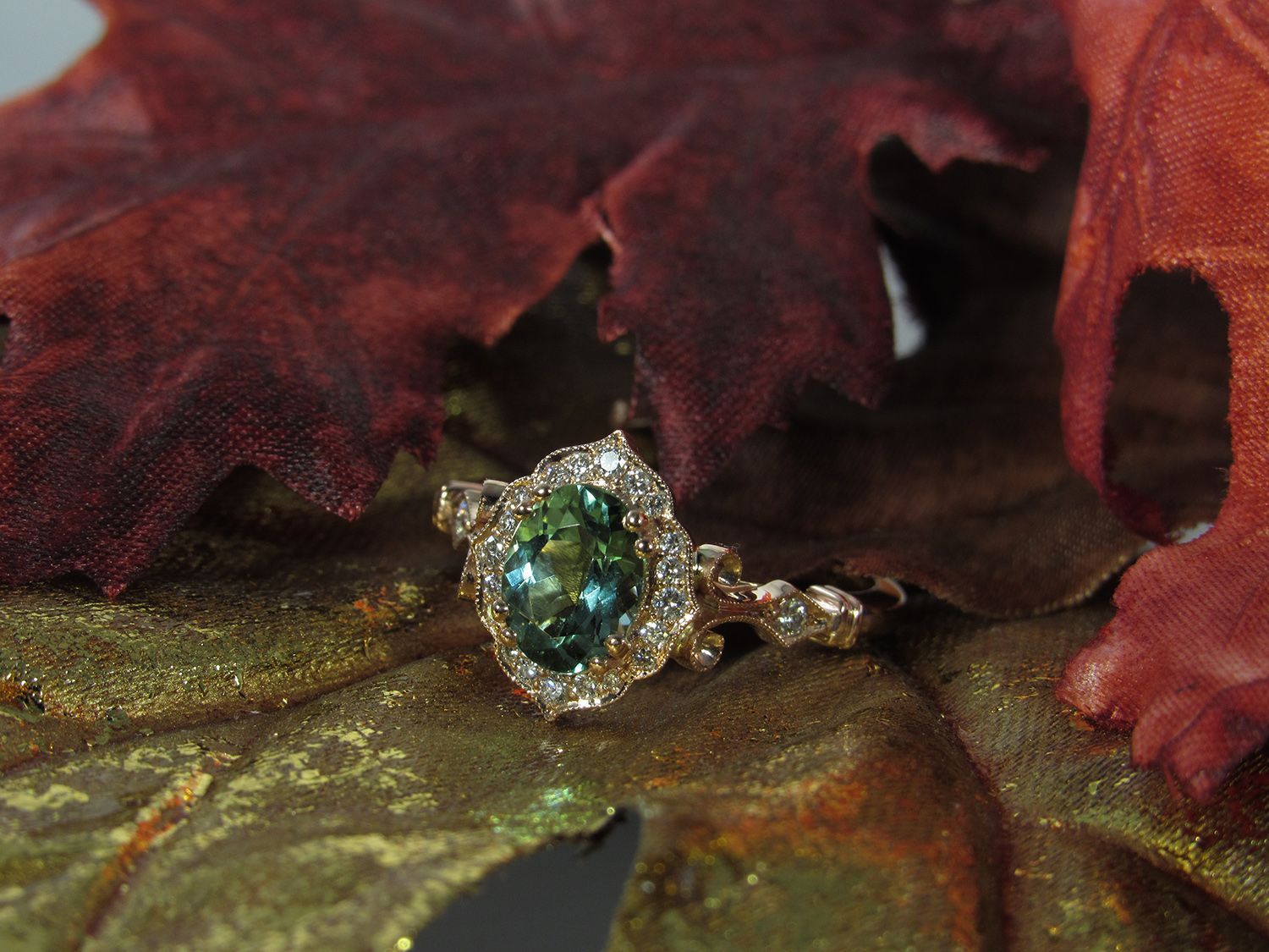 A ring with a green stone is sitting on a leaf