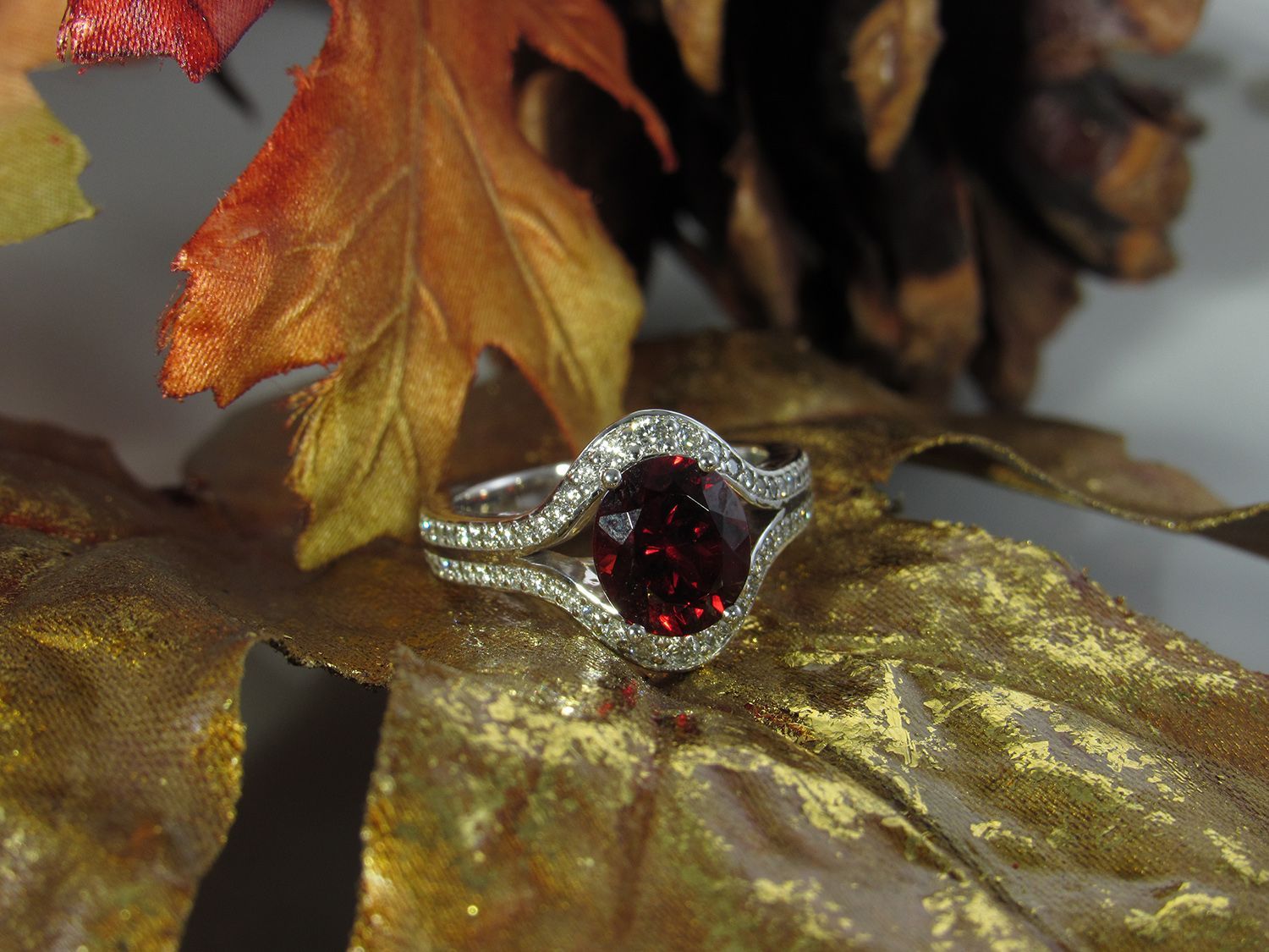 A ring with a red stone is sitting on a leaf