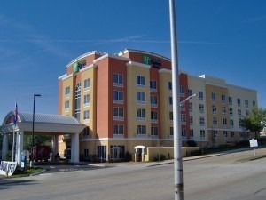 A multi-story Holiday Inn Express hotel building with tan and orange exterior walls under a clear blue sky.