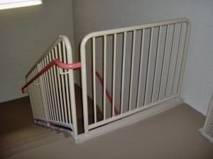 White metal railings and a red handrail installed along a staircase in a corner.