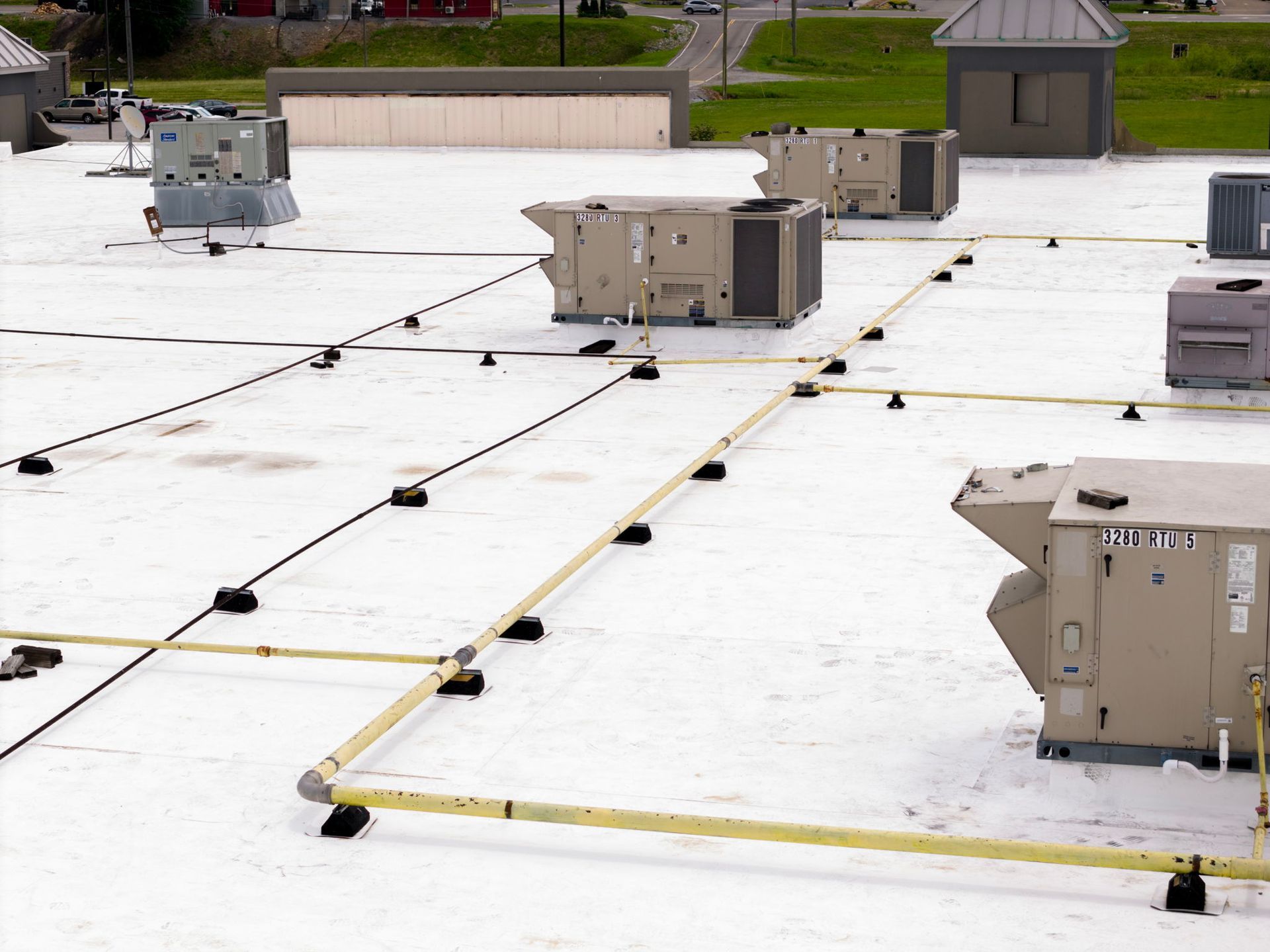 Flat white rooftop with HVAC units and yellow safety lines