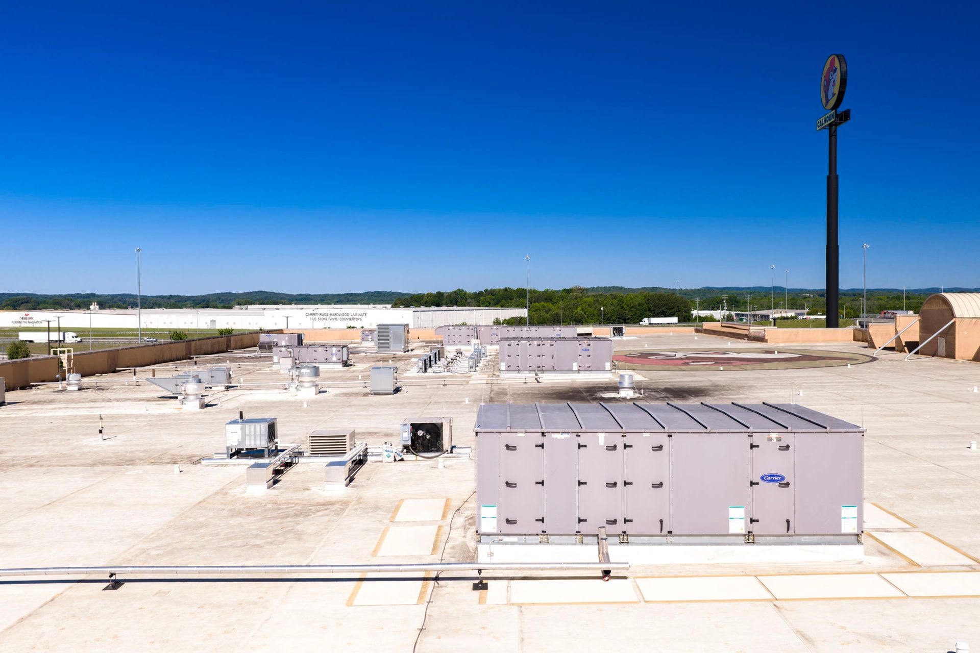 Rooftop HVAC units on a flat white roof under a clear blue sky