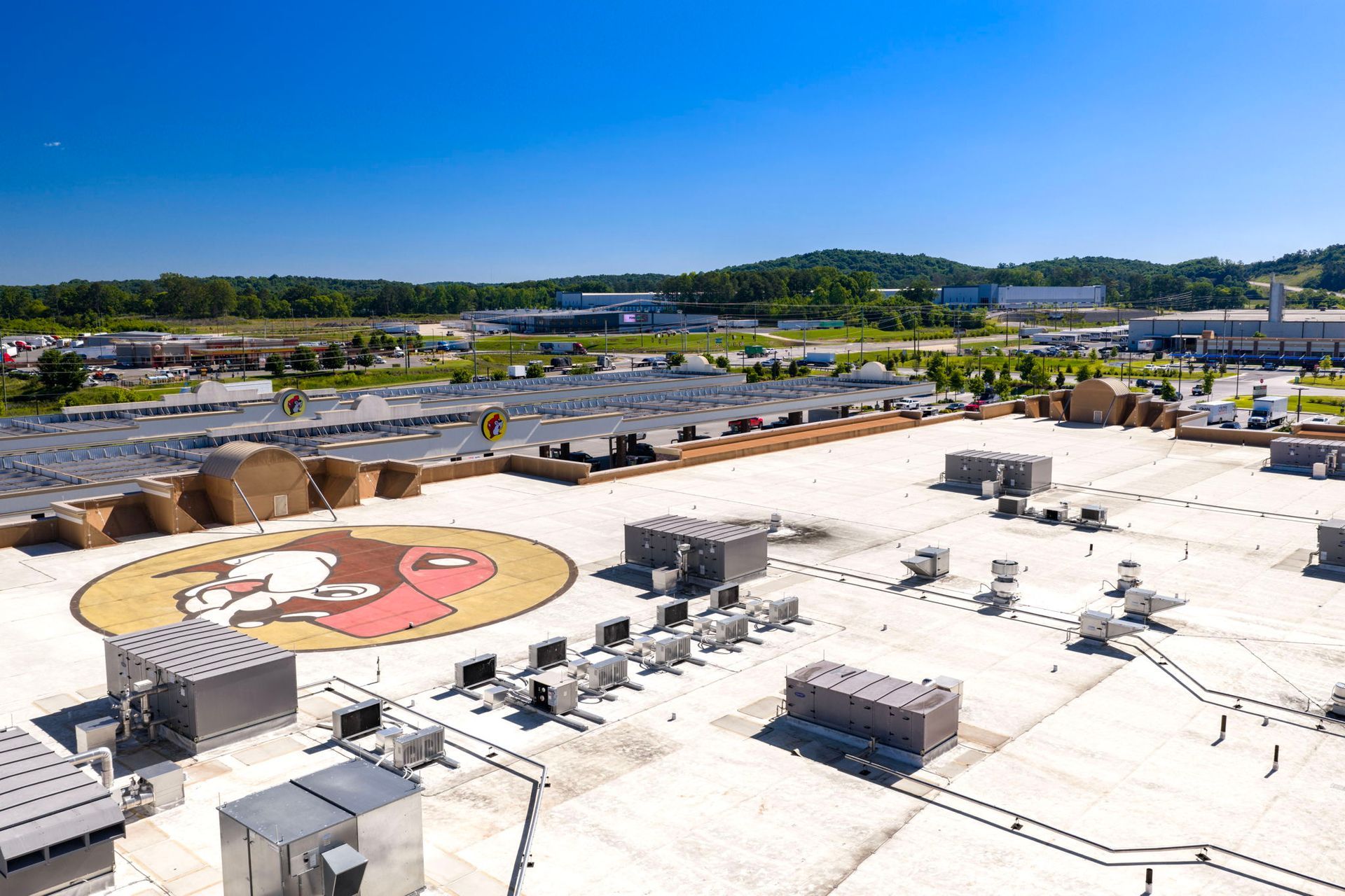 Rooftop with a large cartoon face mural, HVAC units, and distant hills under a clear sky