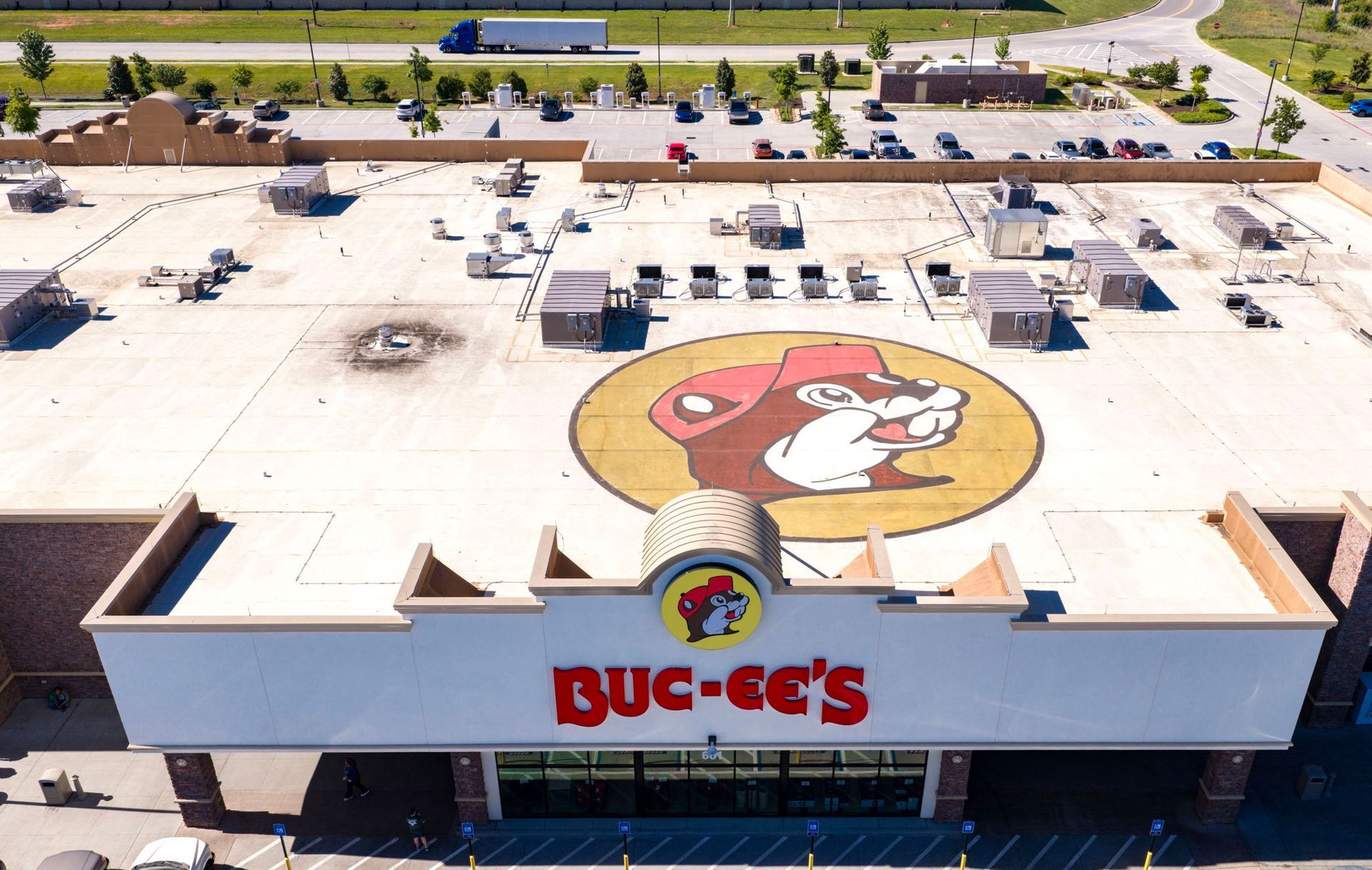 Aerial view of a Buc-ee’s store roof with the beaver logo and parking lot below.