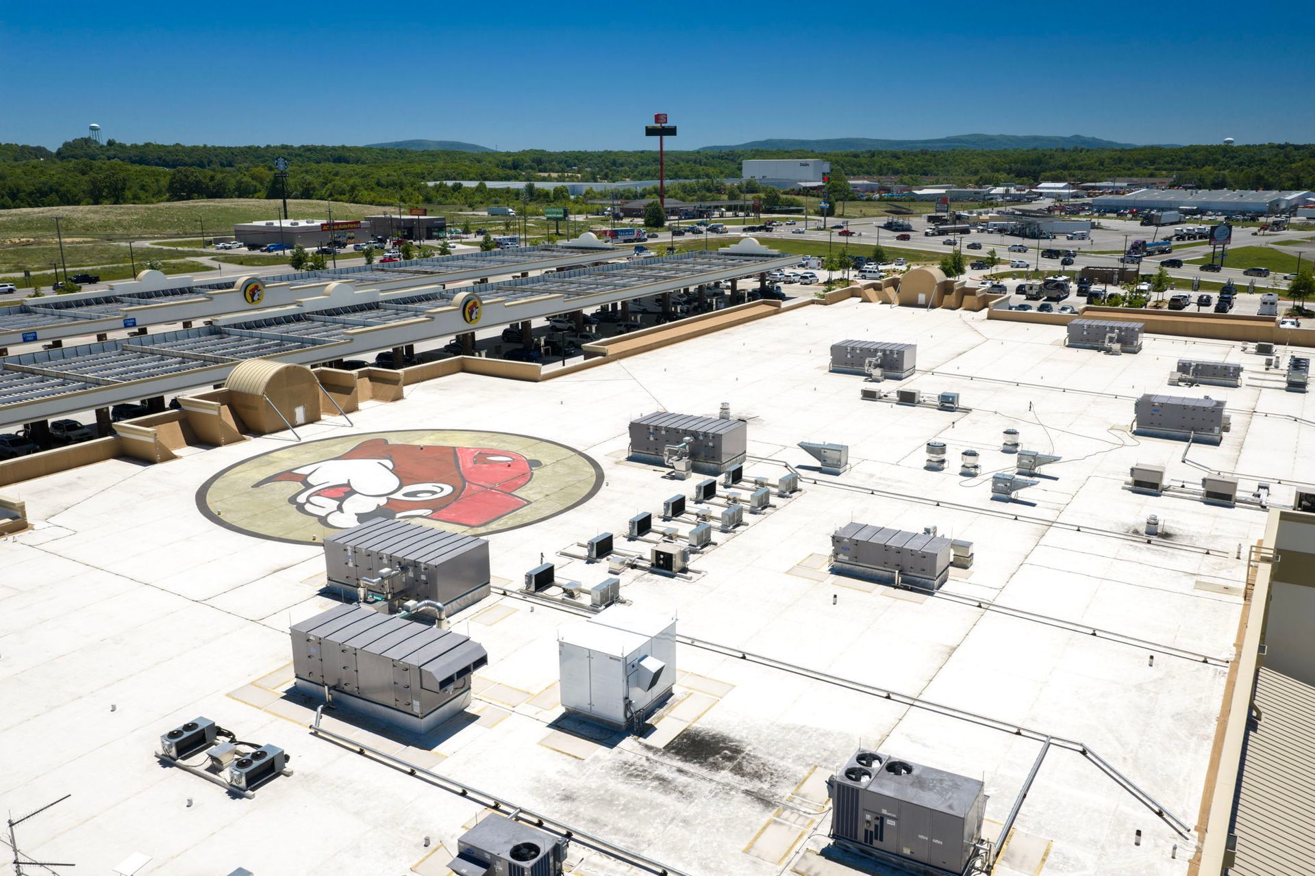 Aerial view of a large white-roofed complex with a circular logo painted on the roof.