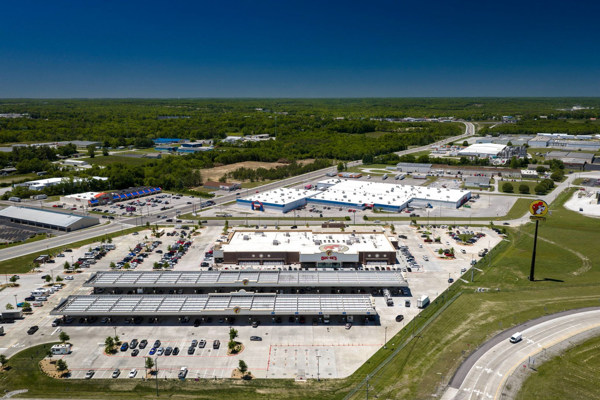 Aerial view of a large shopping center with parking lots, roads, and surrounding greenery