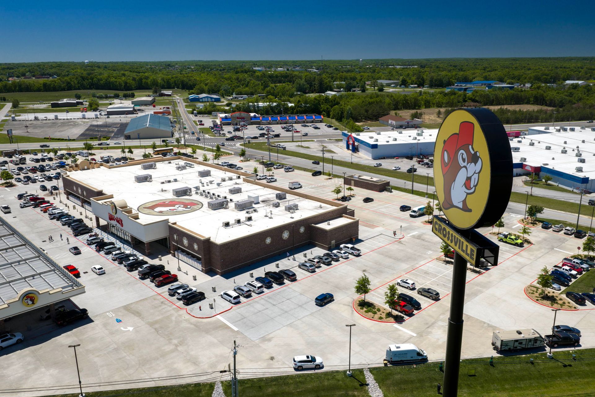 Aerial view of a Walmart store and parking lot on a sunny day, with a large sign in the foreground.