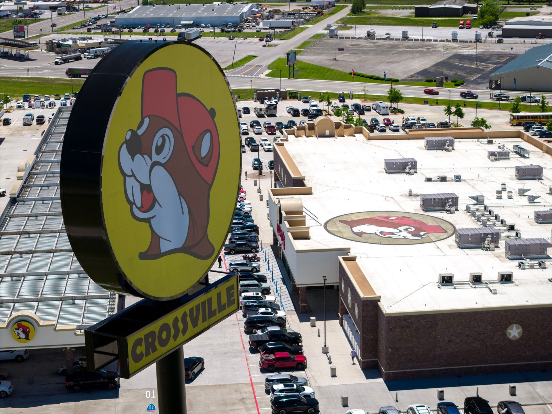 Aerial view of a large gas station with a giant circular Buc-ee’s beaver sign and parking lot.