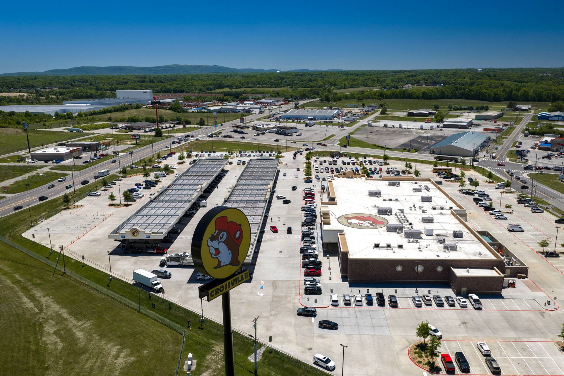 Aerial view of a Buc-ee’s gas station and parking lot with many cars under clear blue sky.