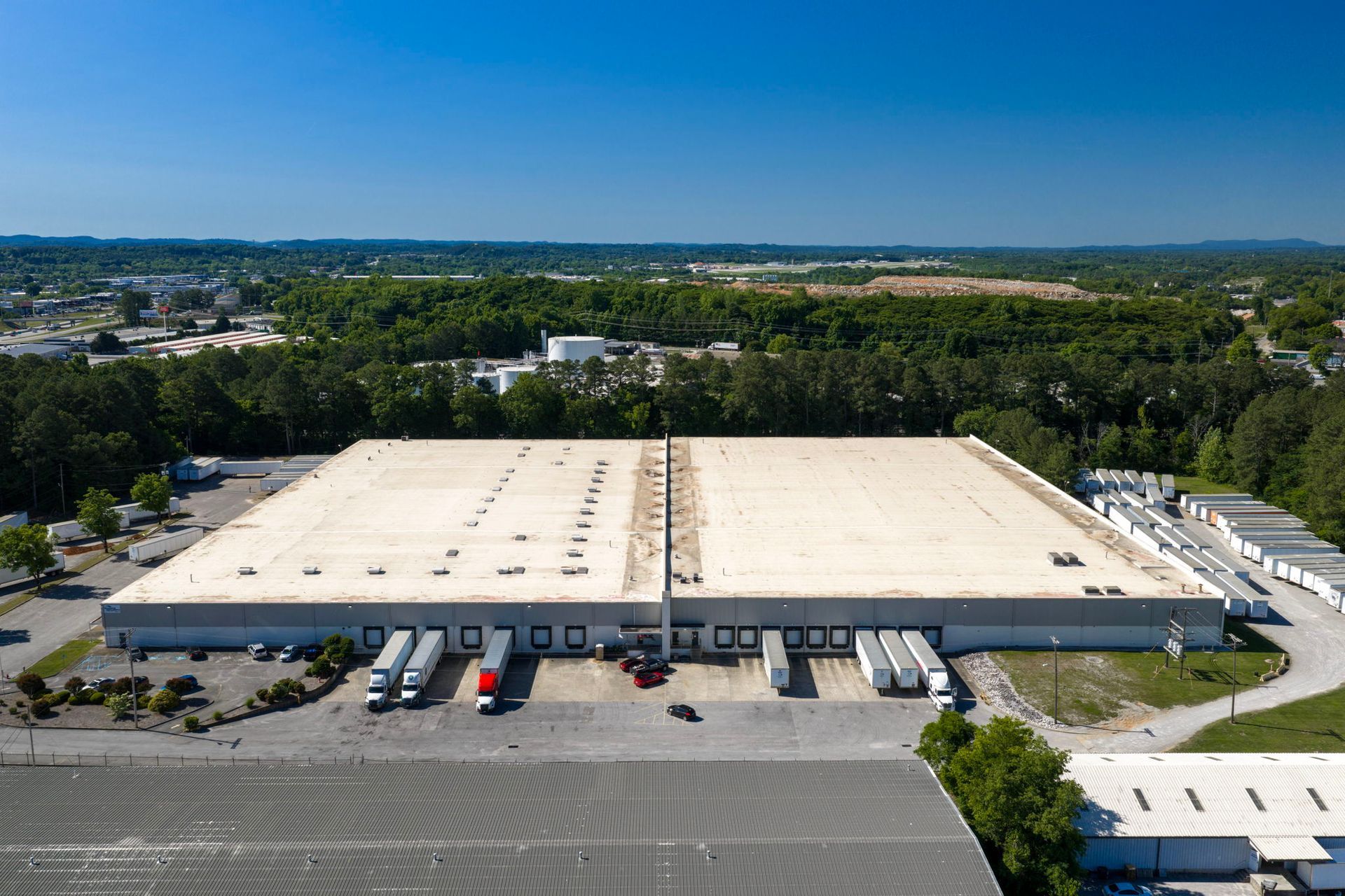 Aerial view of a large warehouse with trucks parked at loading docks in an industrial area.