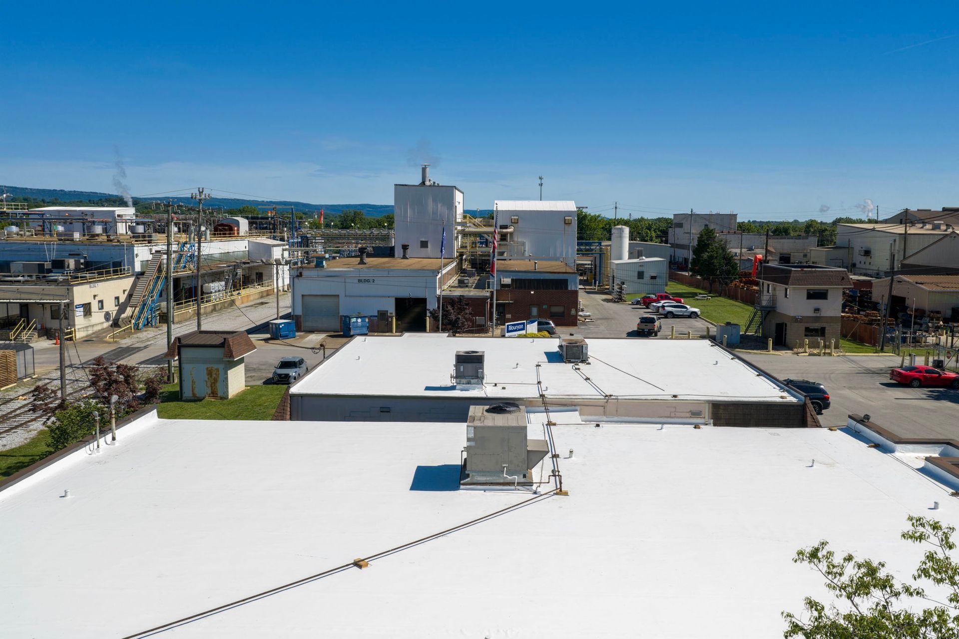 Rooftop view of a sunny coastal neighborhood with low buildings and a blue sky