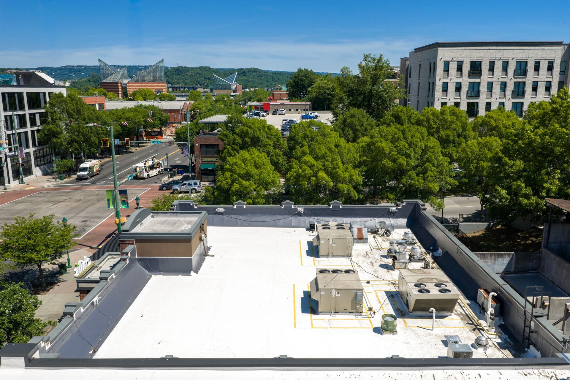 City campus view with white rooftop, trees, streets, and buildings under a clear blue sky