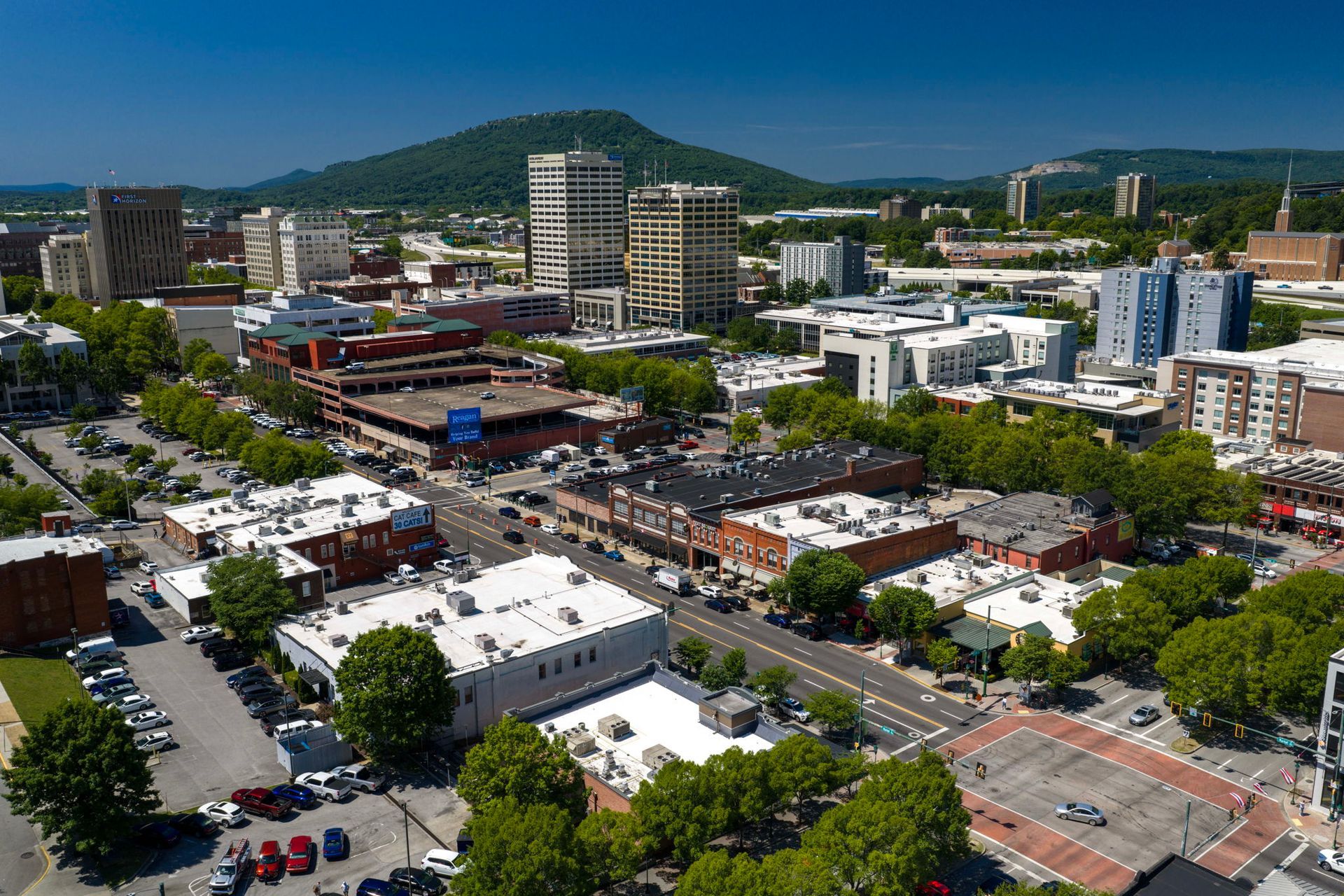 Aerial view of a downtown with streets, buildings, trees, and mountains in the background