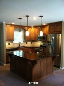 A kitchen interior featuring wooden cabinets, a dark granite island, stainless steel appliances, and three pendant lights.