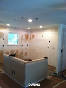 A kitchen under renovation with unpainted drywall, recessed lighting, and exposed electrical boxes on the walls.
