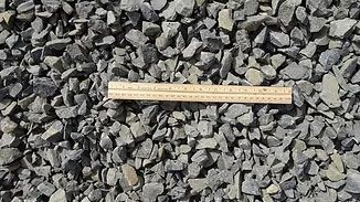 Wooden ruler lying horizontally on gray gravel stones.