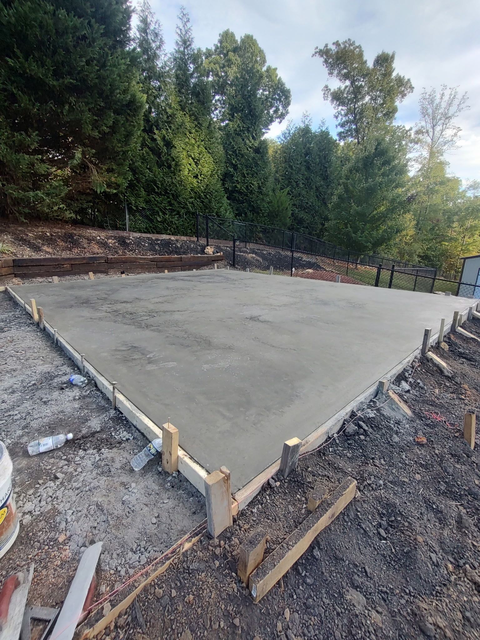 Freshly poured concrete slab with wooden forms at a wooded construction site