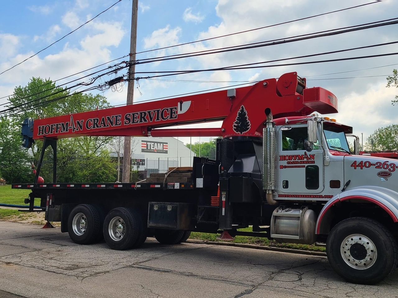 A truck with a crane attached to it is parked on the side of the road