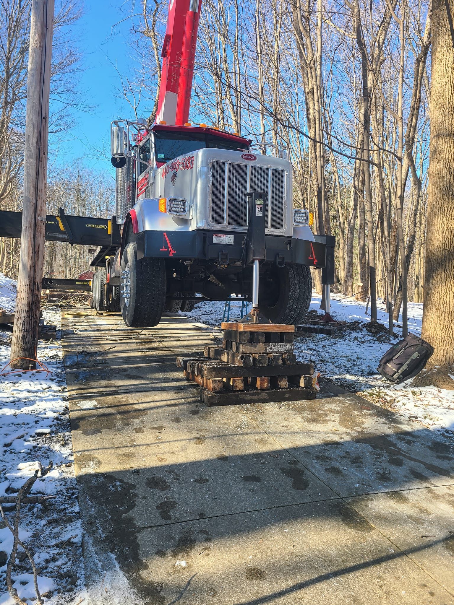 A large truck with a crane on top of it is parked on a snowy road.