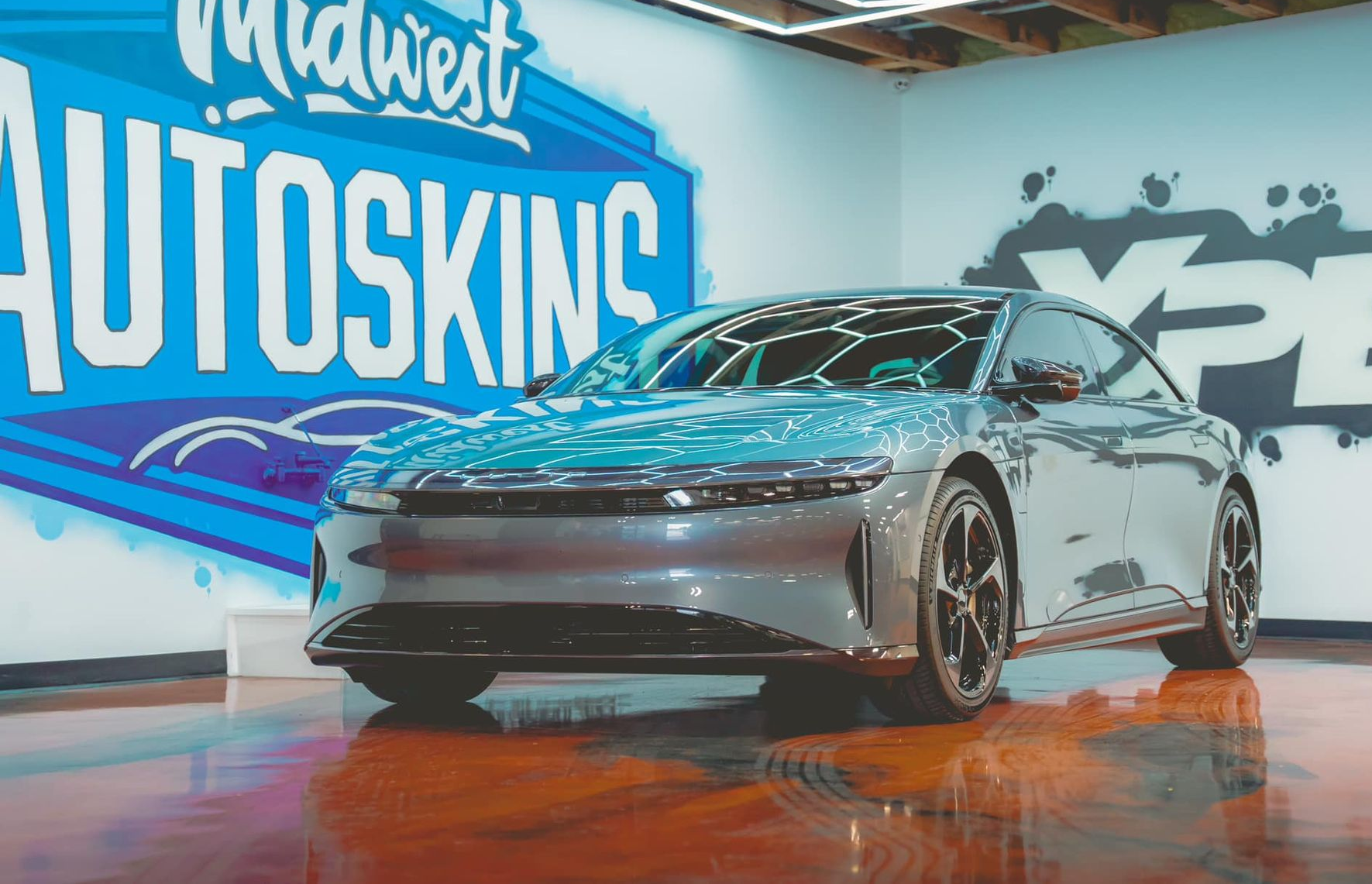 A shiny silver Lucid Air car parked inside a shop with