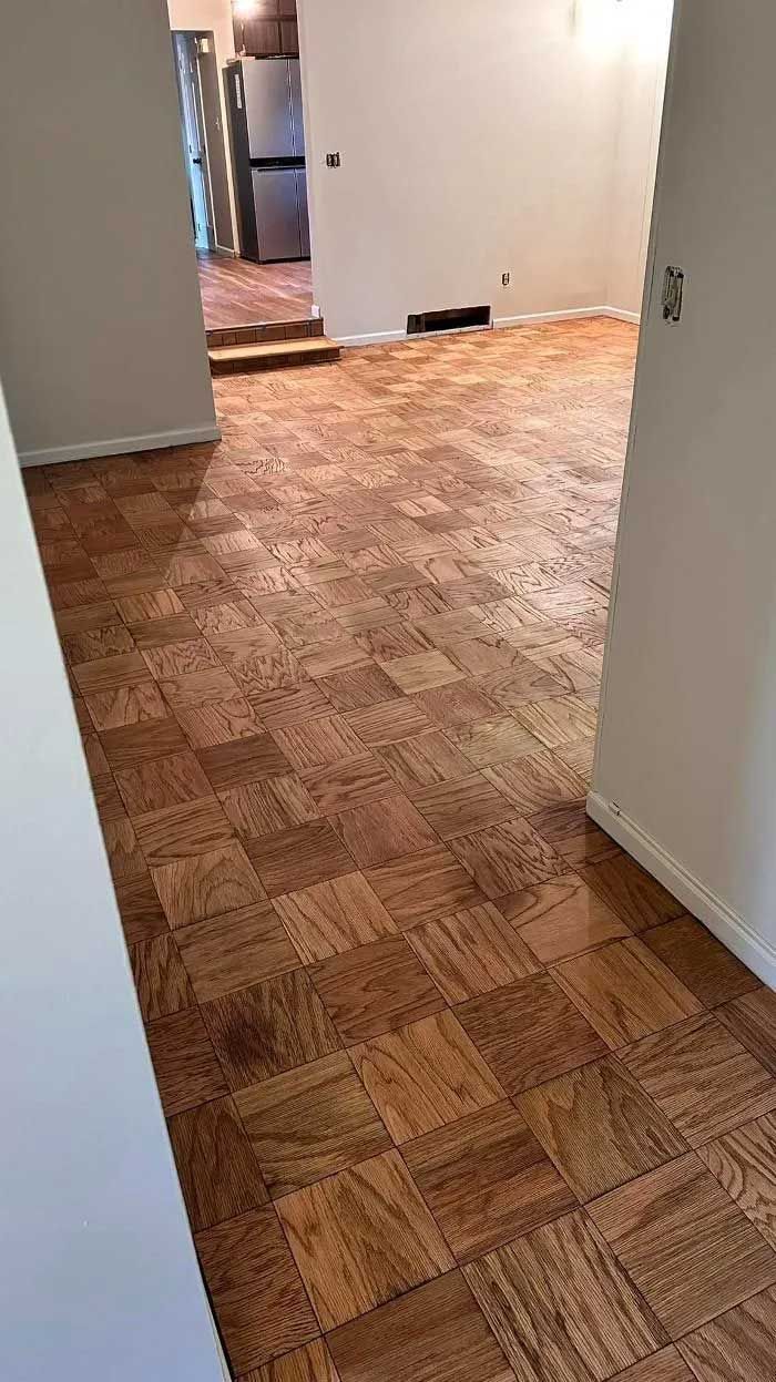 Wooden parquet flooring in an open room. Doorways lead to further rooms.