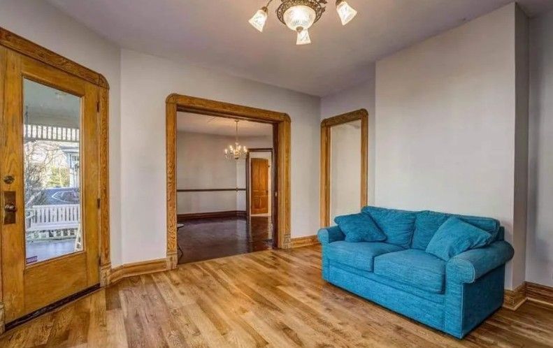 A room with hardwood floors, blue couch, and wooden door frames.