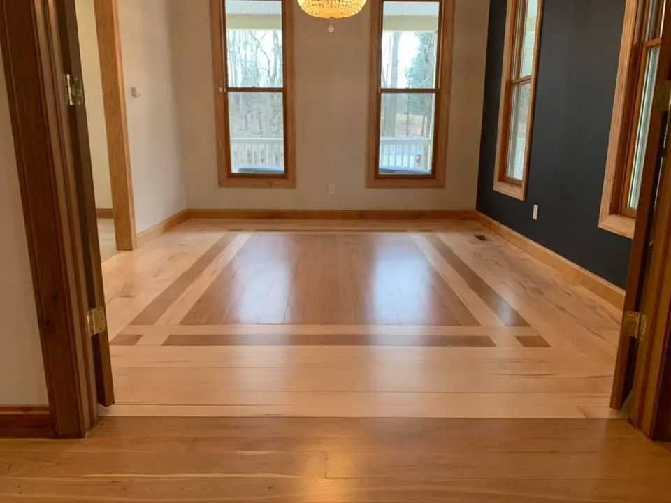 Hardwood floors in a room with windows and a black wall.