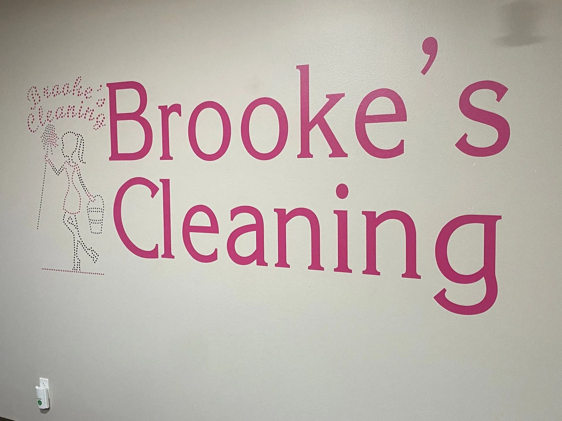 Pink “Brooke’s Cleaning” wall sign on a light gray wall.