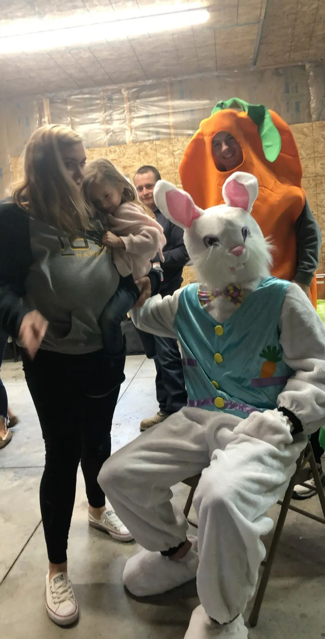 Costumed people posing indoors; one in a white bunny outfit sits in front, others stand behind.