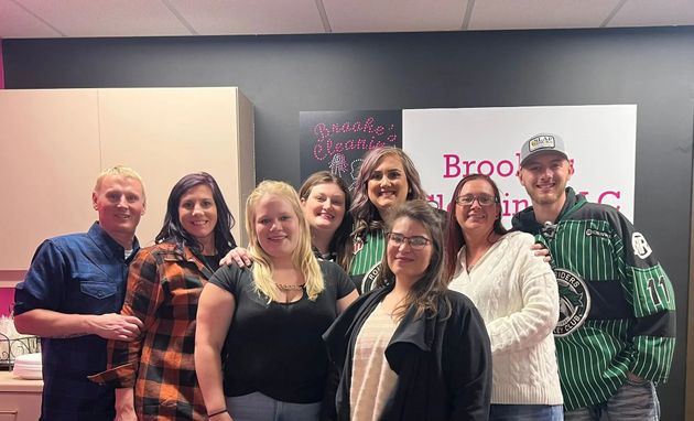 Group of smiling people standing indoors in front of a presentation banner.