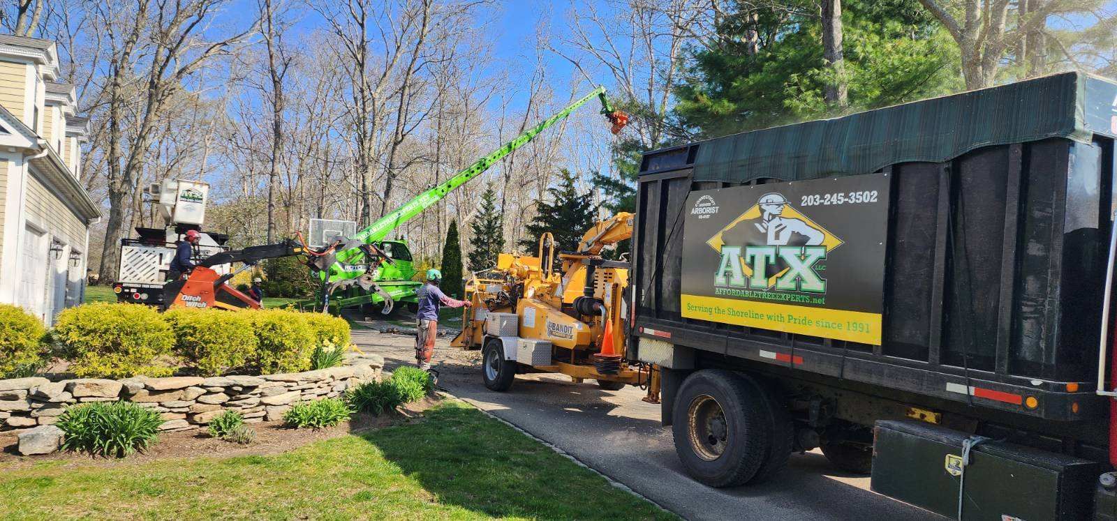 A truck with a chipper attached to it is parked in front of a house.